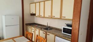 a kitchen with a sink and a microwave and a refrigerator at LAGO AZUL 45 in Breña Baja +2 photos