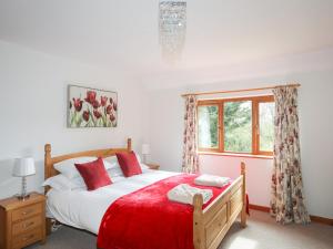 a bedroom with a bed with a red blanket and a window at Long House in Beaumaris