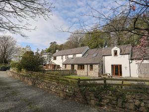 a white house with a stone fence in front of it at Long Cottage in Beaumaris