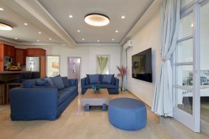 a living room with blue couches and a table at Soultouch Beachfront Villa in Perissa