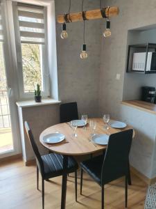 a dining room with a wooden table and chairs at JDK Apartamenty Legionów 32m2 4-osobowy in Kalisz