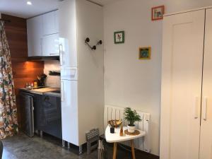 a kitchen with a white refrigerator and a small table at Charmant studio neuf tout équipé terrasse vue imprenable, parking facile gratuit in Lézigneux