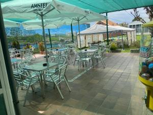 un patio al aire libre con mesas, sillas y sombrillas en Hostal Restaurante Río Ubierna, en Quintanilla-Vivar