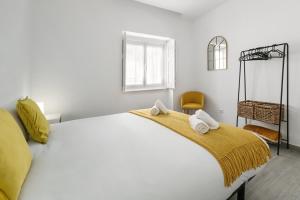 a bedroom with a large white bed with towels on it at Refúgio da Nazaré in Nazaré