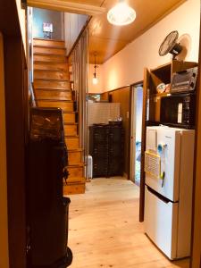 a hallway of a house with a refrigerator and stairs at Guest House Toranjyo-lit in Tamano