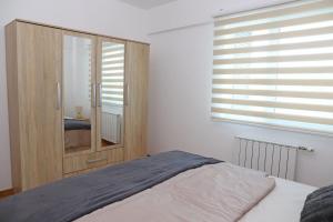 een slaapkamer met een houten kast en een bed bij Apartment Cecovic - Mellain in Tuzla +12 foto's