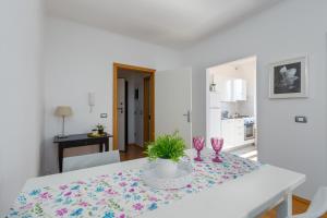 a white dining room with a table with two wine glasses at Apartment San Giovanni - Sea View in Rovinj