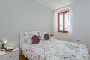a white bedroom with a bed and a window at Apartment San Giovanni - Sea View in Rovinj