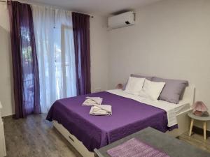 a bedroom with a bed with purple sheets and a window at apartmani Žganec in Baška