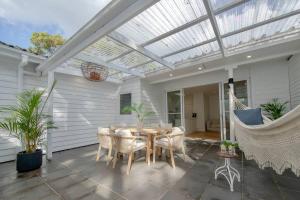 a conservatory with a table and chairs on a patio at SALTY SNOOZE - Your Coastal Holiday House in Avalon