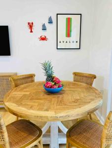 una mesa de madera con un bol de fruta. en SALTY SNOOZE - Your Coastal Holiday House en Avalon