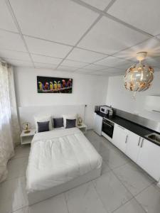 a white bedroom with a white bed and a kitchen at Hello-Guyane, Marina 3, Studio Prestige 5 étoiles in Saint-Laurent du Maroni +27 photos