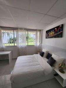a white bedroom with a large bed and windows at Hello-Guyane, Marina 3, Studio Prestige 5 étoiles in Saint-Laurent du Maroni