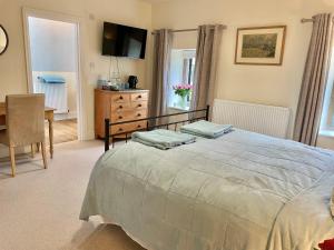 a bedroom with a bed and a table and a television at Parsonage House, Badminton in Great Badminton