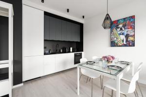 uma cozinha e sala de jantar com uma mesa de vidro e cadeiras brancas em Stara Cegielnia Lake View Apartment by Renters Prestige em Poznań