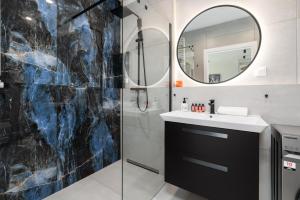 a bathroom with a shower and a sink and a mirror at Stara Cegielnia Lake View Apartment by Renters Prestige in Poznań