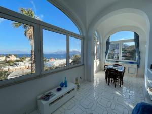 um quarto branco com uma mesa e algumas janelas em Casa Franca appartamento vista mare em Capri