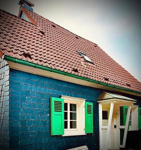 ein blaues Gebäude mit grünen Fenstern und einem Dach in der Unterkunft Gästehaus zum Alten Feilenhauer in Remscheid