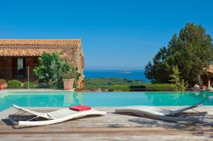 a pool with two lounge chairs next to a house at Chambres d'Hôtes Littariccia in Porto-Vecchio