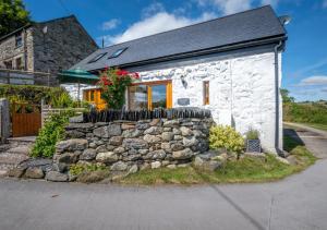 a small white cottage with a stone wall at Ysgubor Wen in Llanrwst