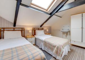 two beds in a attic bedroom with a window at Waldo Hafod y Mor in Tenby