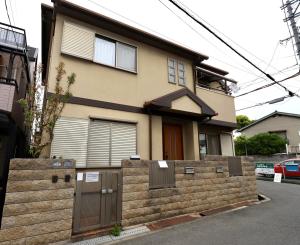 a house with a fence in front of it at Guest House Kubo Homes Shotenshita in Osaka