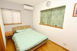a bedroom with a bed and a window with a clock at Guest House Kubo Homes Shotenshita in Osaka