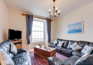 a living room with a leather couch and a coffee table at Waldo Hafod y Mor in Tenby