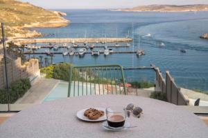 Gozo Harbour Views, Mgarr Heights في Mġarr: طاولة مع طبق من الطعام وكأس من النبيذ