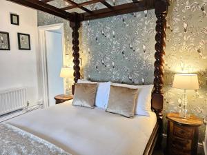 1 dormitorio con cama con dosel y pared con papel pintado en College Arms en Stratford-upon-Avon