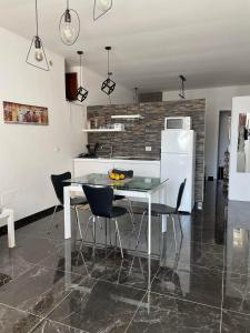 una cucina con tavolo in vetro e sedie nere di Ortigia Loft Via Malta, 22 a Siracusa