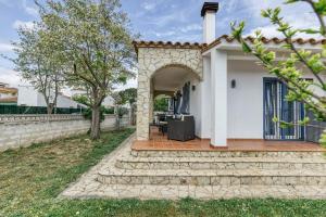 a white house with an archway in the yard at Casa Elena in Sant Pere Pescador
