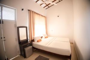 a bedroom with a bed and a mirror and a window at Lankahuts Villa in Negombo