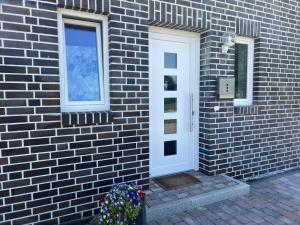 a brick building with a white door and a window at Ferienwohnungen EBBE und FLUT - Niedrigenergiehaus in Elpersbüttel