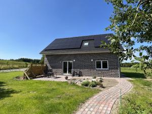una casa de ladrillo con paneles solares en el techo en Ferienwohnungen EBBE und FLUT - Niedrigenergiehaus, en Elpersbüttel