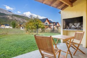 a wooden table and chairs on a patio with a view of a field at Alojamiento Amor Amarillo in El Bolsón