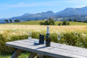 a bottle of wine sitting on a picnic table with two glasses at Waenfechan Glamping in Colwyn Bay