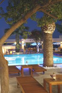 einen Pool mit Bänken und Bäumen in einem Hotel in der Unterkunft Glaros Beach Hotel in Hersonissos