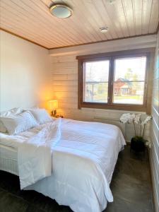 a bedroom with a large white bed with a window at Himos Mökki superior - Chalet Cottage superior ski-in-ski-out in Jämsä
