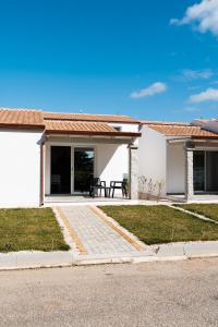 Cette maison blanche dispose d'une terrasse et d'une table. dans l'établissement Villetta 6 La Caletta, à La Caletta