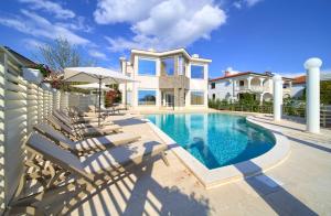 a house with a swimming pool with chairs and an umbrella at Villa PIANO in Pinezici