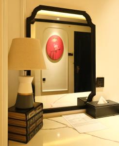 a bedroom with a mirror and a lamp on a dresser at Nicecy Boutique Hotel in Ho Chi Minh City