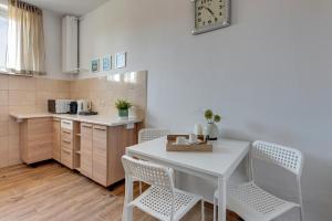 Il comprend une petite cuisine avec une table et des chaises blanches. dans l'établissement Downtown Apartments Old Town Stolarska, à Gdańsk