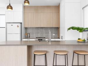 a kitchen with wooden cabinets and a counter with stools at Palmera on the south coast in Ulladulla