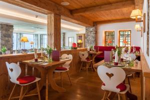 AllgäuHotel Tanneck في فيشن: مطعم بطاولات خشبية وكراسي بيضاء