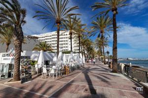 een promenade met palmbomen en stoelen en een gebouw bij RENOVATED HOUSE IN OLD TOWN MARBELLA. in Marbella