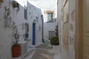 a narrow alley with white buildings and blue doors at Tholari project by S. in Astypalaia