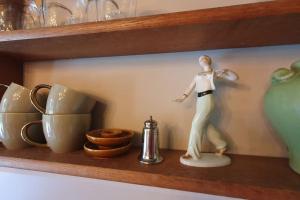 une figurine d'une femme sur une étagère avec des tasses dans l'établissement Landelijk gelegen appartement met eigen ingang, à Nieuwediep