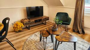 a living room with a tv and a chair and a table at Logements neufs à Bannalec Centre in Bannalec