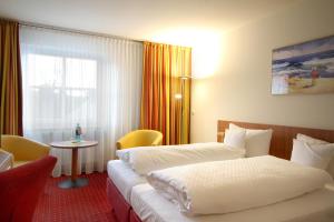 a hotel room with two beds and a table at Morada Hotel Arendsee in Kühlungsborn